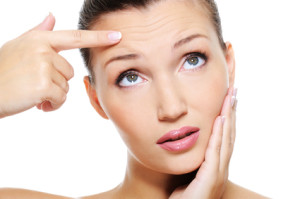 woman showing by index finger the wrinkles on her  forehead